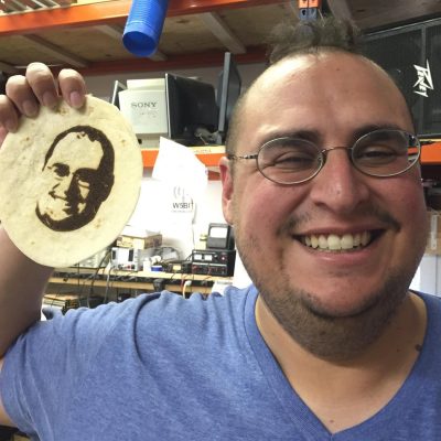 Dr. Joey Lopez holding a tortilla with an imprint of his face on it.