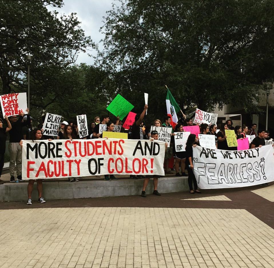 Students holding up a large sign that reads, "More students and faculty of color."