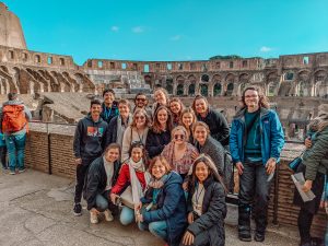 COMM to Italy Students pose in front of the Roman Colosseum