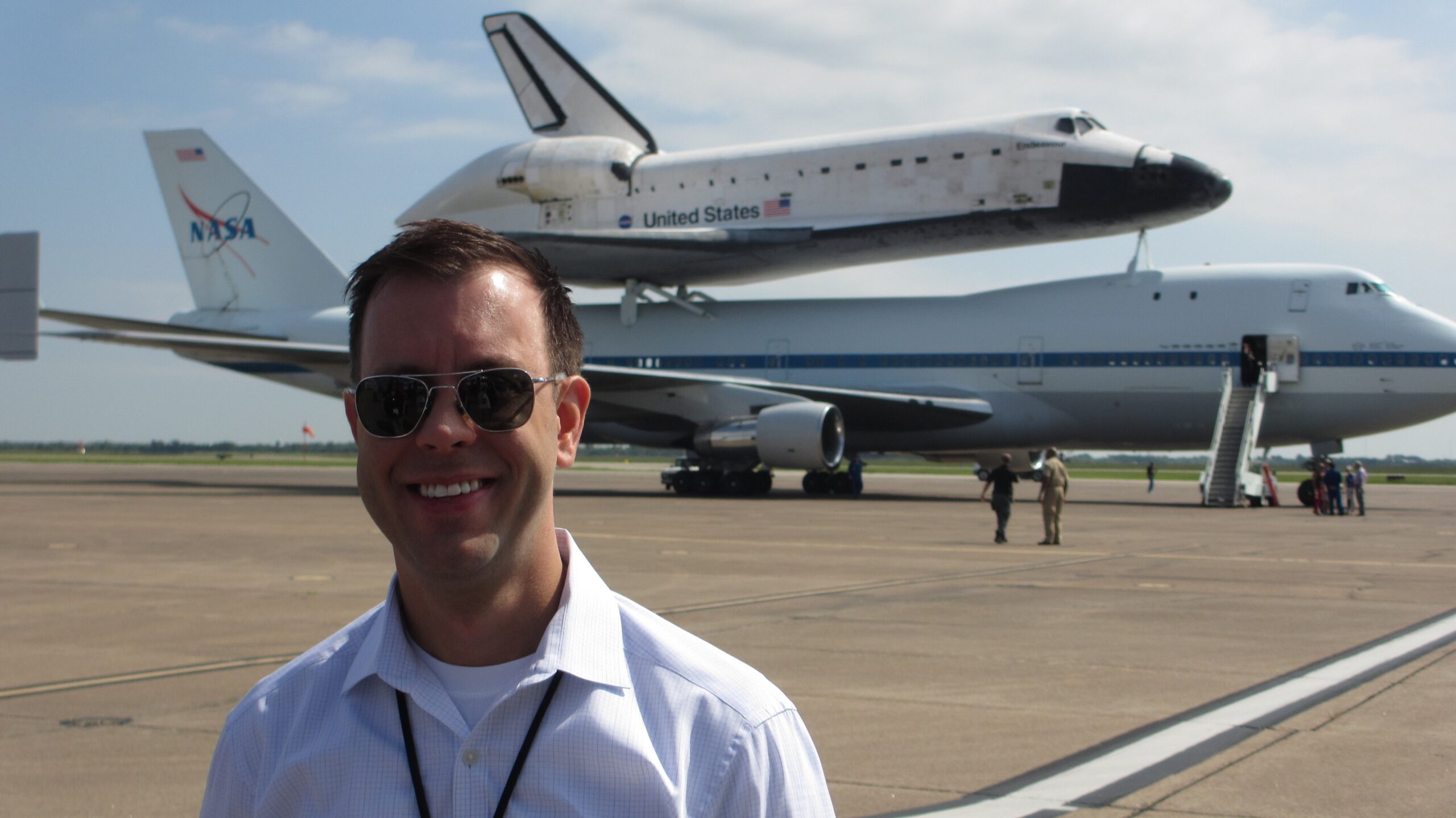 Josh Byerly '99 on the tarmac with the Space Shuttle Endeavour atop a NASA Shuttle Carrier Aircraft in the background. 