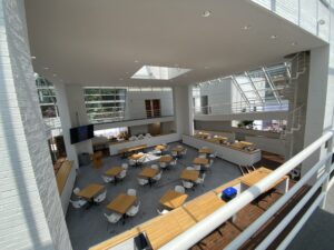 Picture overlooking a room with many sets of brown tables and white chairs.