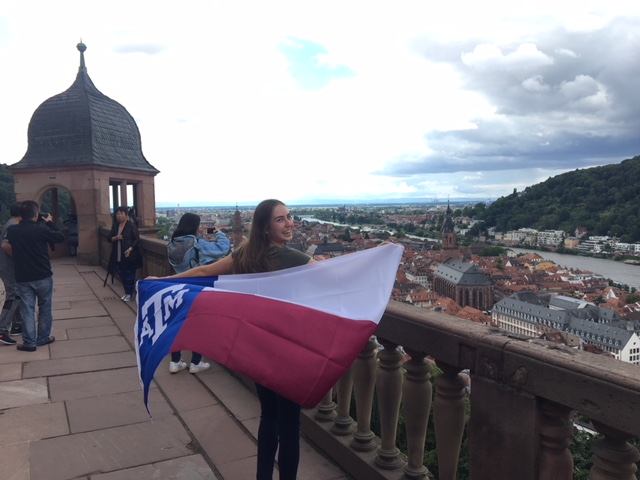 Student holding Aggie flag at Schloss Heidelberg overlooking the town of Heidelberg, Germany.