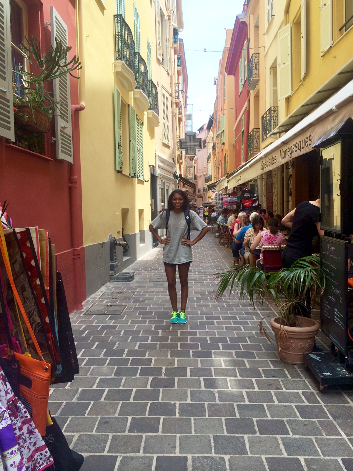 Student standing in front of colourful shop facades on a narrow side street in Spain.
