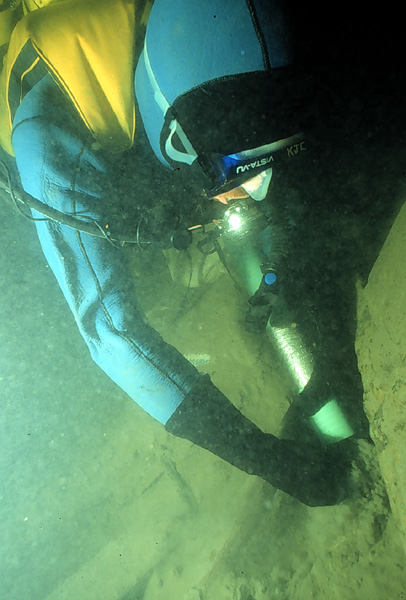 A diver removes soft lake bottom sediment from the interior of the ferry wreck with a water dredge.