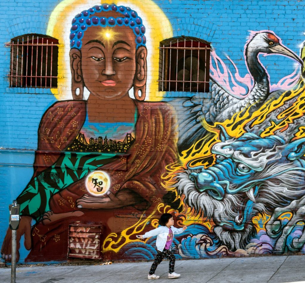 colorful asian art wall mural with asian american child in front of it