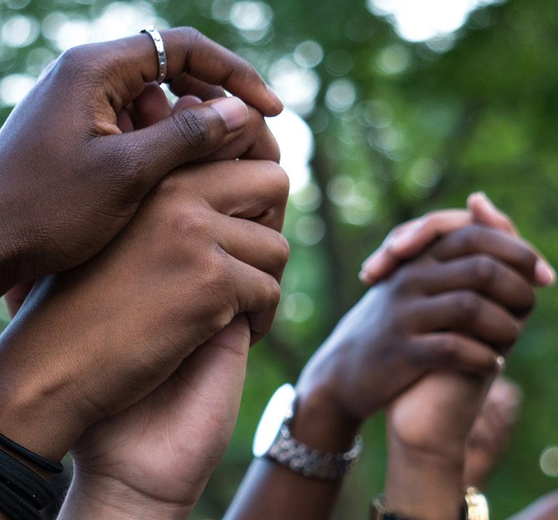 hands of different skin colors raised in unity