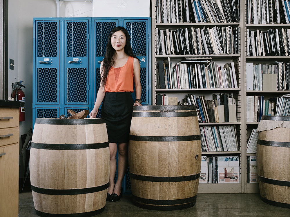 Photo of Grace Tsai posing with the barrels of food in a lab.