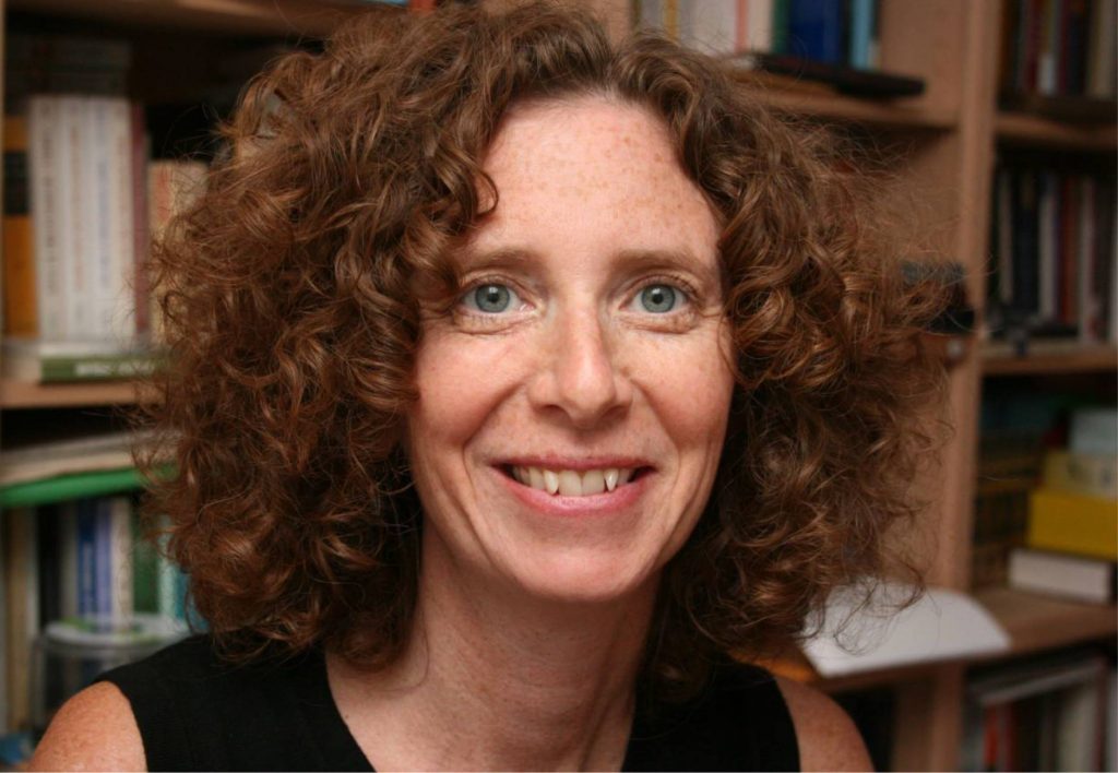 Headshot of Claire Katz, curly auburn hair and green eyes.
