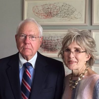 Jack Benson '63 stands on the left wearing a dark suit and red and blue tie. Carol Benson, his wife, stands on the right wearing a pink and gray striped sweater.