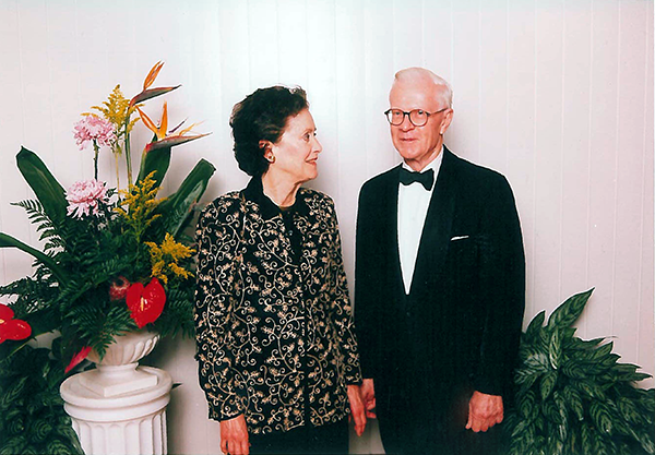 Samuel R. Gammon III (right) wears a tuxedo and stands next to his late wife, Mary, who wears a black jacket with gold filigree.
