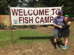 Andrew Millar '14 and Paige Hellman '15 posing next to a banner that reads "Welcome to Fish Camp"