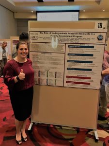 Rollins standing next to poster for undergraduate research