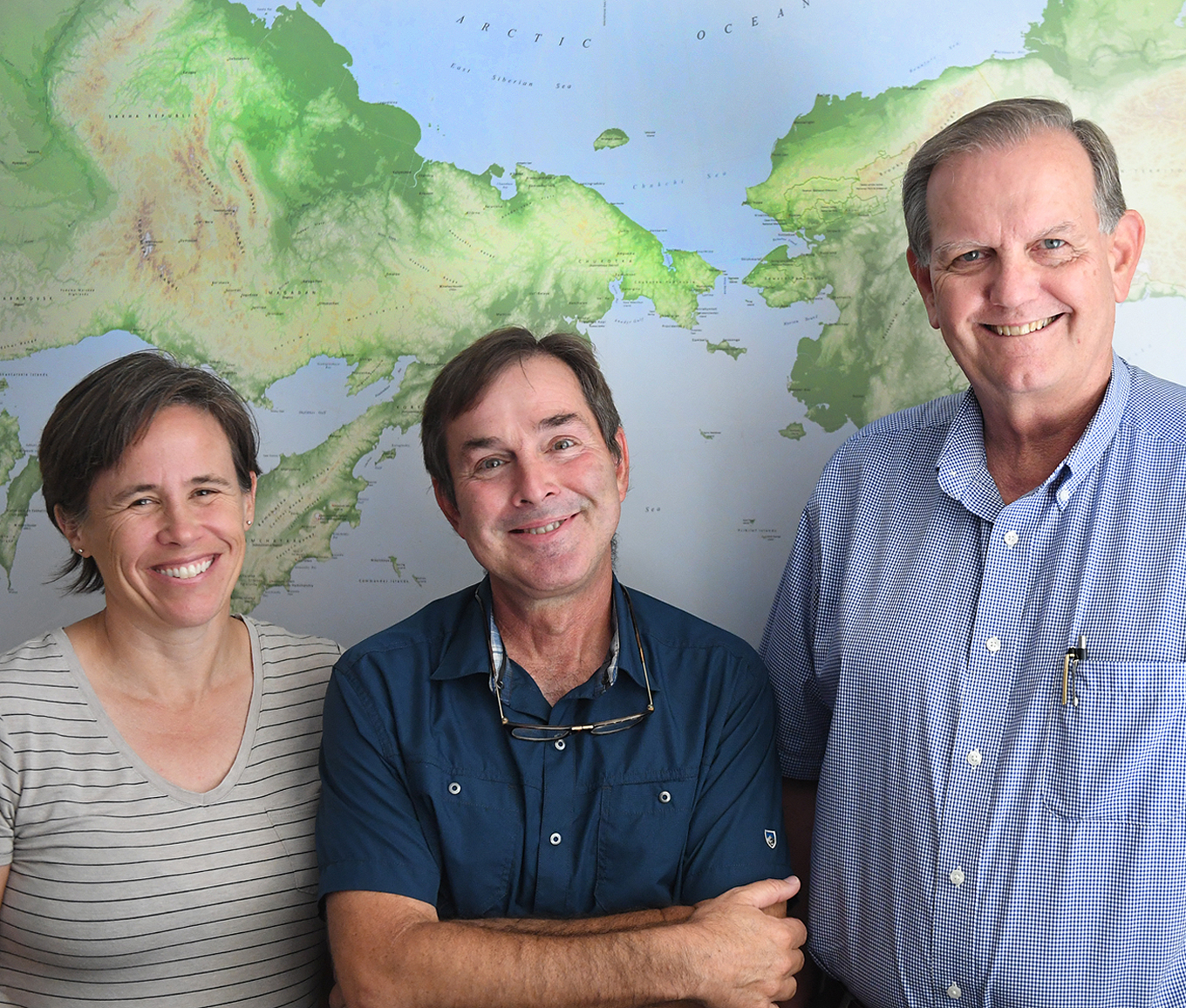 From left to right: Kelly Graf, Ted Goebel and Michael Waters of the Center for the Study of the First Americans, stand in front of a map showing where modern man crossed over from present day Siberia to North American while standing in their offices at The Anthropology Building on the A&M campus.