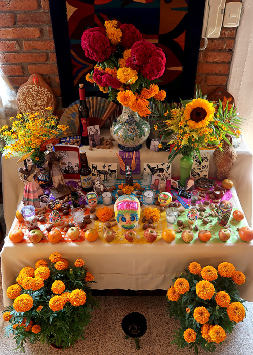 Day of the Dead offering with symbolic flowers, foods, and decorations.
