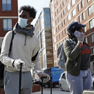Students wearing face masks move out of dorms