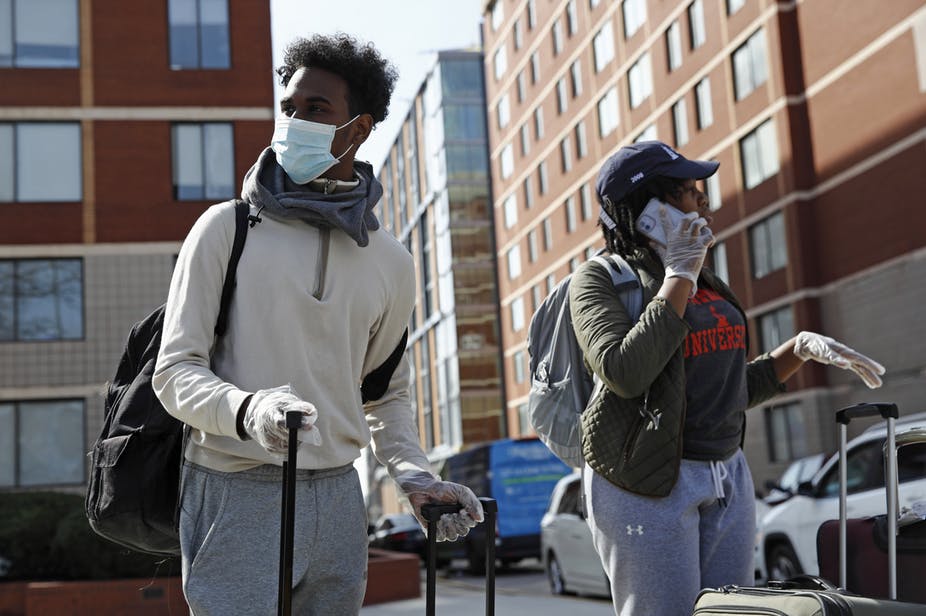 Students wearing face masks move out of dorms