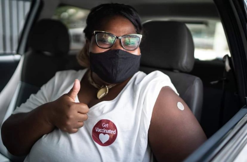 After receiving the COVID-19 vaccine in a drive-through vaccination center, a lady gives a gig 'em with a smile behind her mask.