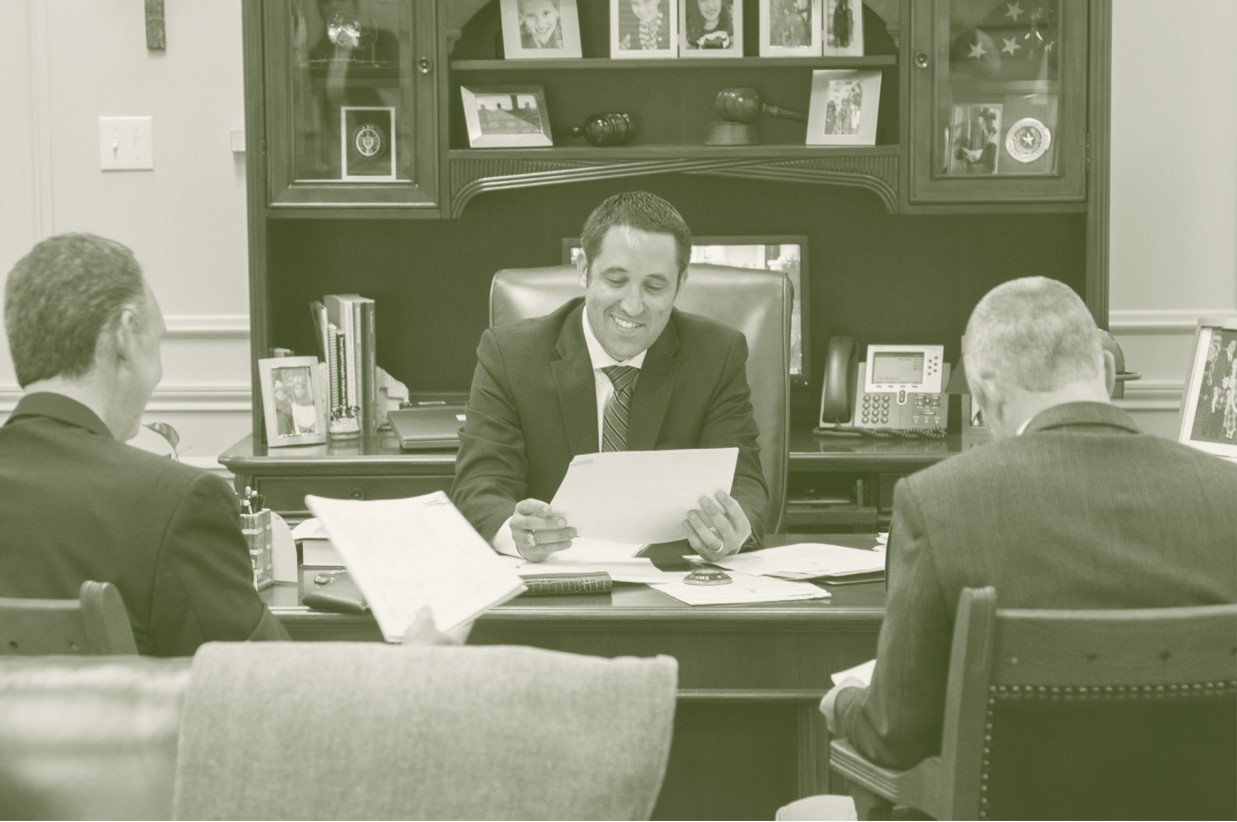 Green and white photo of Hegar presenting a report as the state Comptroller.