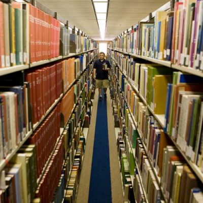 A student walking through the shelves of books at Sterling C. Evans Library at Texas A&M.