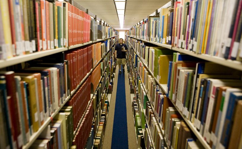 A student walking through the shelves of books at Sterling C. Evans Library at Texas A&M.