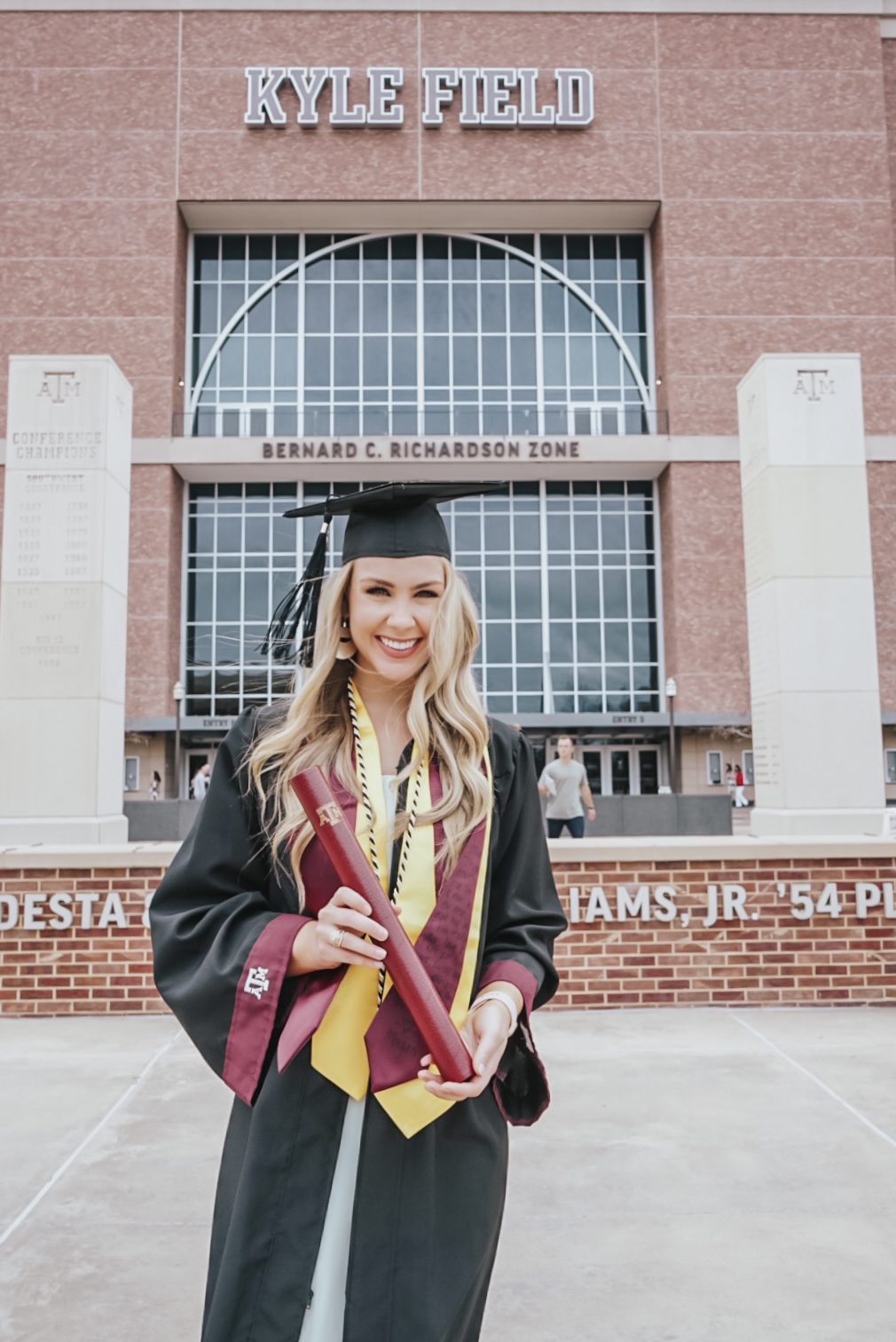 Fuller in cap and gown in front of Kyle Field.