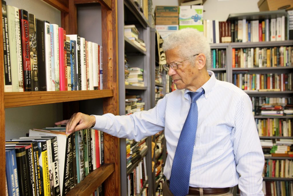 Dr. Albert Broussard pulls a book from the shelf in his office.