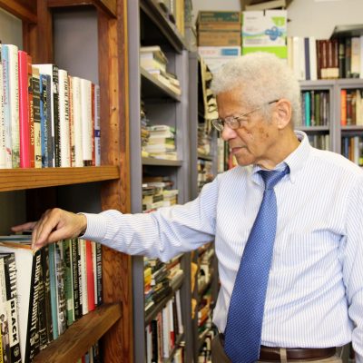 Dr. Albert Broussard pulls a book from the shelf in his office.