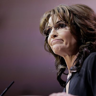 Sarah Palin stands in front of a microphone on a podium.