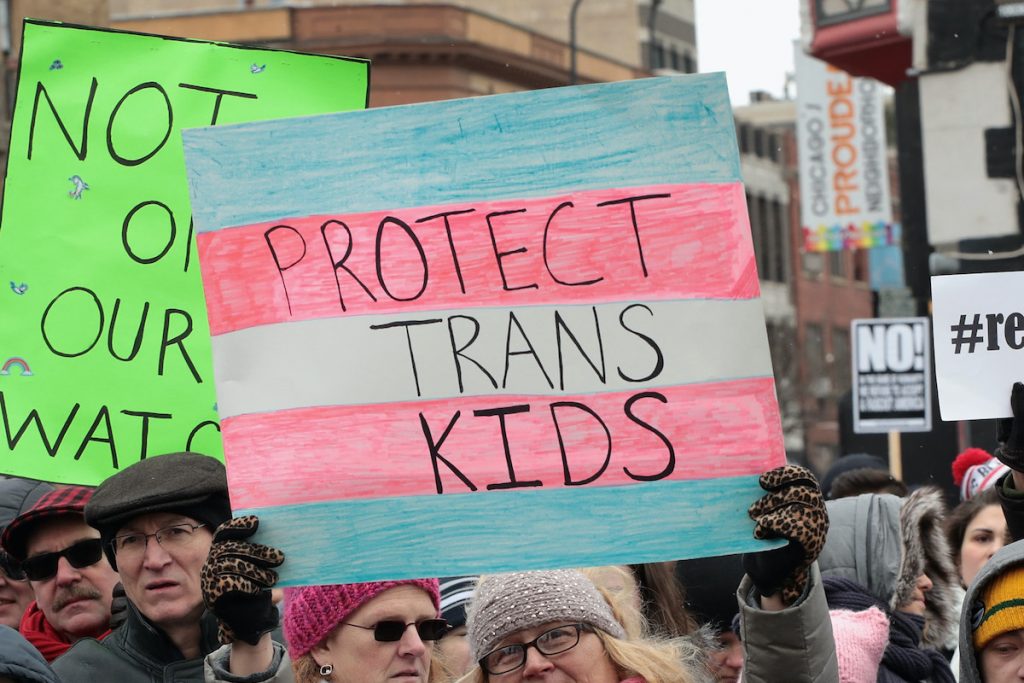 Woman holding sign that reads "Protect trans kids."