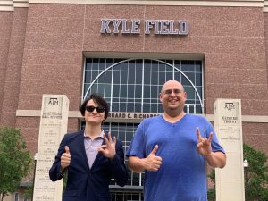 Dr. Joey Lopez and professor Jonathan Guajardo stand in front of Kyle Field holding up the hand signs for their colleges and Texas A&M. 