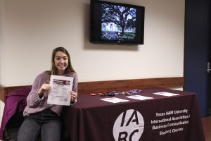 Picture of Andi Minter holding an IABC flyer in Bolton by the IABC table.