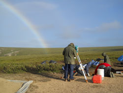 workers on dig with rainbow in background