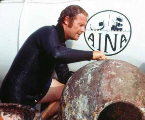 Dr George Bass in wetsuit inspecting large artifact